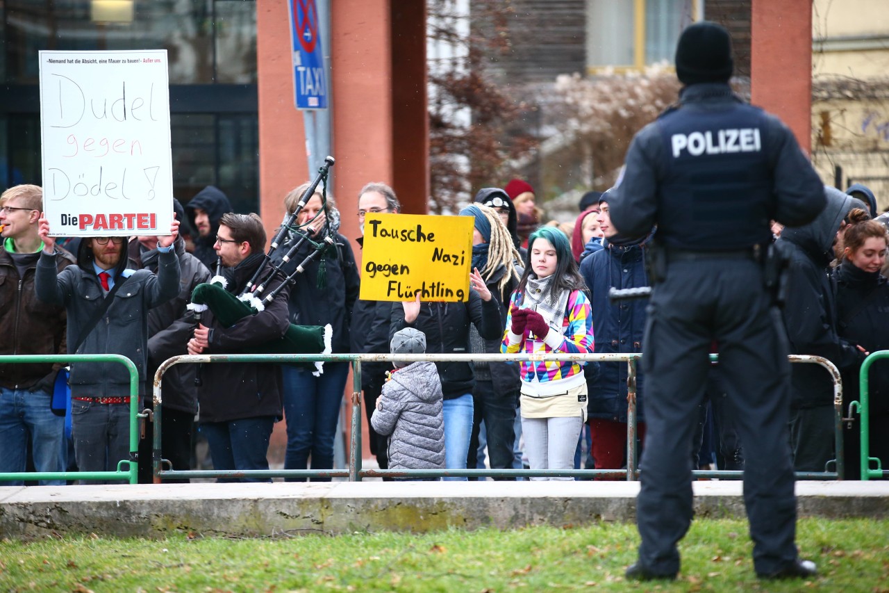 Demonstranten protestieren hinter einer Absperrung unter anderem mit dem Plakat "Tausche Nazi gegen Flüchtling" gegen eine rechte Demonstration zum Gedenken von Luftkriegstoten.