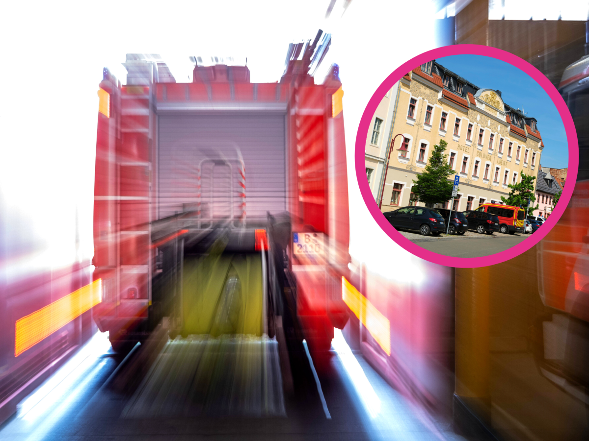 Feuerwehrauto von hinten mit Hotel in der Ecke