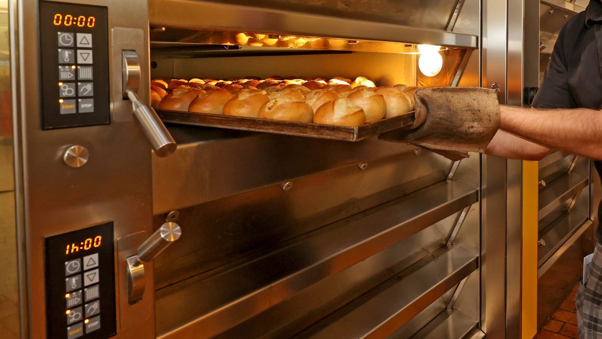 BÃ¤cker nimmt frische BrÃ¶tchen aus dem Ofen