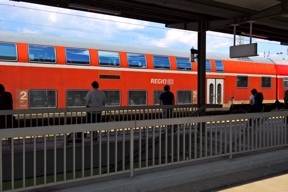 FahrgÃ¤ste stehen am Bahnsteig vor einem Regionalzug