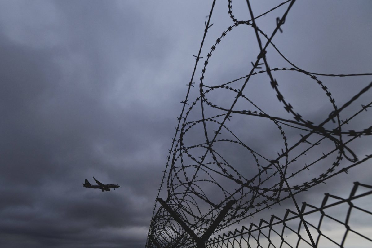 Flugzeug fliegt über einen Zaun mit Stacheldraht